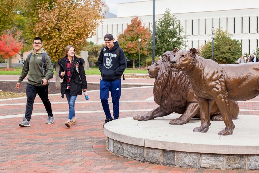 students walking past statues at Widener University campus